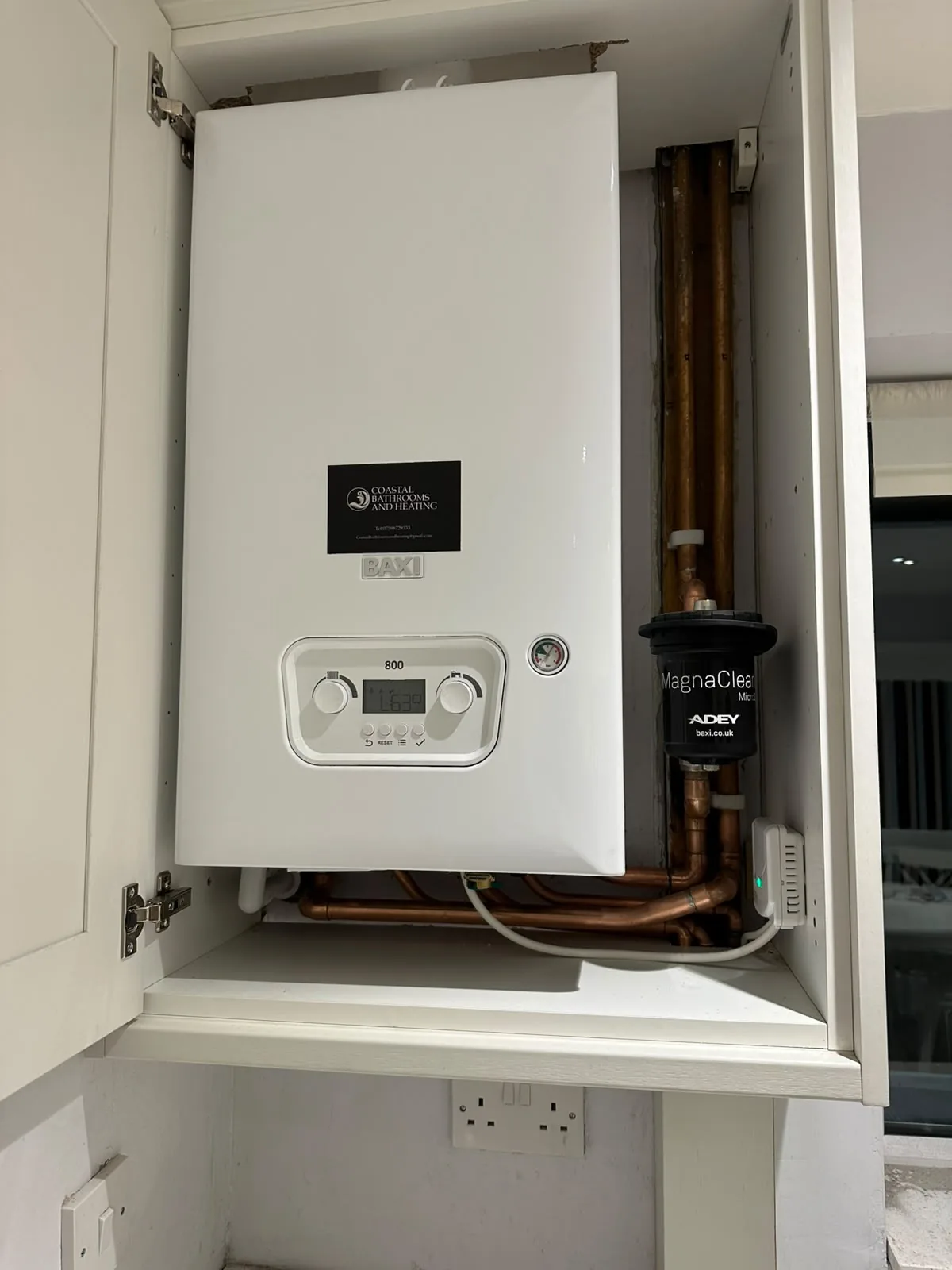 Baxi 800 combi boiler installed inside a white kitchen cupboard with clean copper pipework and a MagnaClean filter
