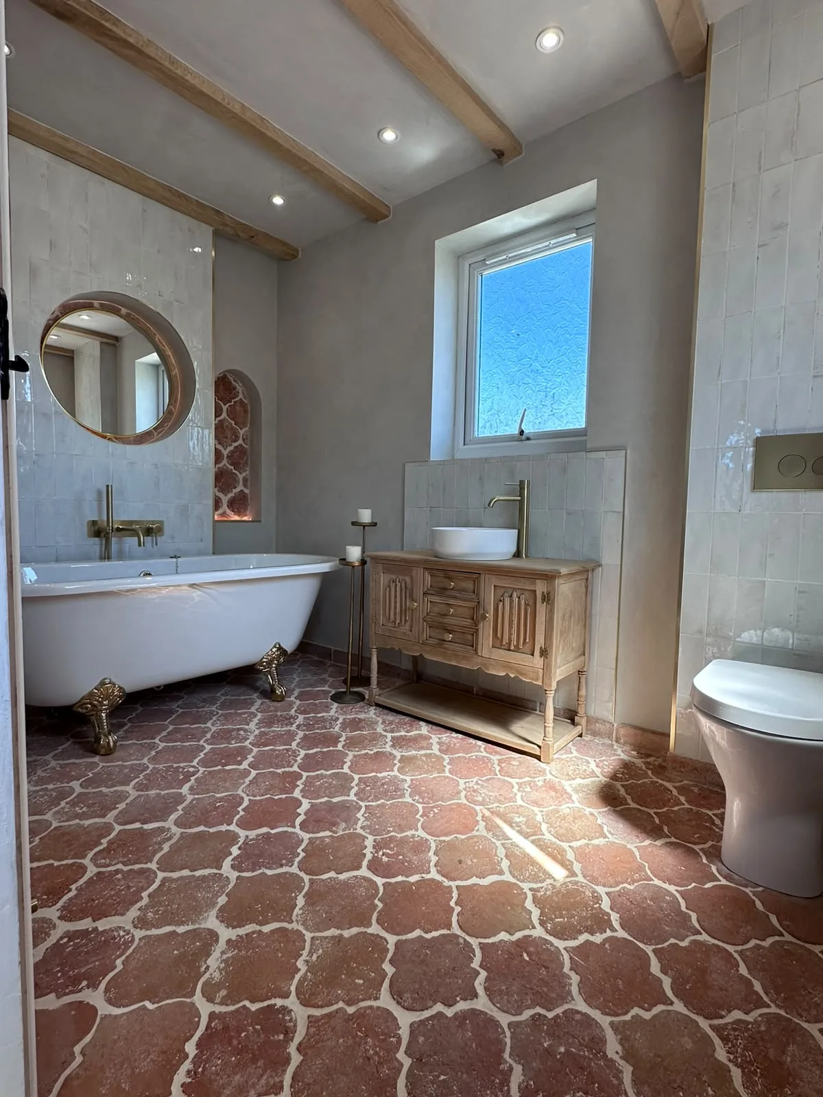 Country bathroom renovation with exposed oak beams, roll top bath, antique timber vanity and terracotta floor tiles